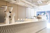 Custom made by Studio Adjective, the 23-foot coffee bar is topped with a white Corian counter and white metal stripes design.  Photo 3 of 10 in A Sleek Coffee Shop in Hong Kong With Beautiful, Minimalist Interiors