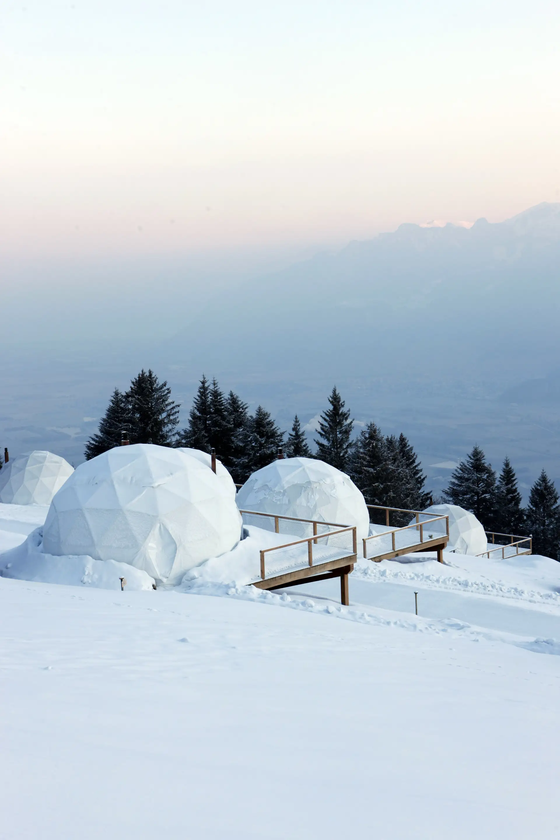 The geodesic domes look like igloos in the snowy Alpine landscape.