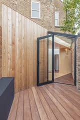Outdoor, Back Yard, Small Patio, Porch, Deck, and Decking Patio, Porch, Deck The patio area floor is finished with a dark-stained decking, surrounding and contrasting the pale-colored plywood.  Photo 8 of 11 in A Crafty Triangular Addition Carves Out Office Space in a London Backyard