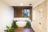 Bath, Stone Tile, Open, Freestanding, Medium Hardwood, and Ceiling The minimalist bathroom captures the atmosphere of the entire property.  Bath Medium Hardwood Ceiling Stone Tile Freestanding Photos from Slip Away to These Sleek New Villas in a Costa Rican Forest