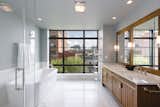 The luxurious master bath has a double vanity, soaking tub, glass-enclosed stall shower, and a wall of windows.