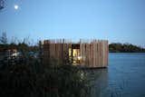 Exterior, Prefab Building Type, Flat RoofLine, Wood Siding Material, and Cabin Building Type After sunset the effect is reversed, and a radiating internal glow emerges from between the wooden slats.  Photo 11 of 13 in Drift Off in a Prefab Cabin at This Floating Hotel in France