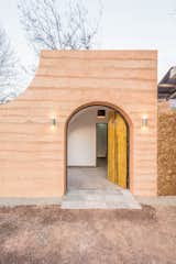 In the renovation of a traditional cave home in Weinan, China, the arched front entrance mimics the curve of the caves, and the wooden front door with contrasting black hinges swings open in two parts.