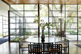 Dining Room, Chair, Table, Medium Hardwood Floor, and Ceiling Lighting The glass wall of windows lets in plenty of natural light.  Photo 5 of 15 in Jerry Bruckheimer Asks $11.9M For This Gem Designed by Thornton Abell