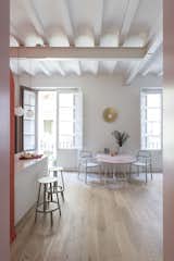 Dining, Stools, Pendant, Wall, Chair, Table, and Light Hardwood Between the two big windows, the golden  Dining Pendant Stools Chair Wall Photos from Before & After: An Ancient Barcelona Apartment Gets a Colorful, Chic Makeover