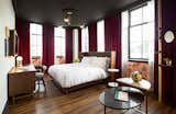 Bedroom, Chair, Pendant Lighting, Bed, Night Stands, and Dark Hardwood Floor Deep dark red velvet floor-to-ceiling curtains paired against bronze lighting and dark wood floors define the vintage vibe in the guest rooms.  Photos from A Former Strip Club Transforms Into a Snazzy Boutique Hotel