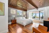 Bedroom, Dresser, Chair, Medium Hardwood, Night Stands, Bed, Table, Lamps, and Track The second bedroom also opens to the terrace and features an ensuite bath.  Bedroom Track Bed Medium Hardwood Photos from A Renovated Harry Gesner–Designed Midcentury in L.A. Wants $9.4M