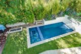 Outdoor, Side Yard, Gardens, Small, Grass, Shrubs, and Trees A view of the pool from the terrace.  Outdoor Gardens Small Grass Photos from A Renovated Harry Gesner–Designed Midcentury in L.A. Wants $9.4M