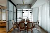 Dining Room, Table, Chair, Medium Hardwood Floor, Rug Floor, Shelves, and Ceiling Lighting The home's industrial look is softened by vintage elements throughout and curtains.  Photos from A Home Office is Cleverly Integrated Into the Living Room of This Compact Condo