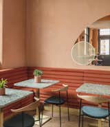 Dining Room, Table, Chair, Bench, and Medium Hardwood Floor Custom-made rust-colored tubular suede banquettes accentuate the sunny color-palette.  Photo 2 of 8 in A Historic London Property Is Converted Into a Modern Mediterranean Eatery