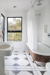 A clawfoot tub and graphic black and white tiles outfit one of the bathrooms.