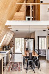 The material palette consists of concrete, bleached flooring, pine plywood, and lots of matte, black-and-white finishes. A loft with a bedroom and full bath has its own deck and overlooks the woods and river.