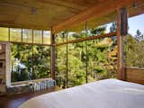 In the sleeping loft, floor-to-ceiling windows overlook a canopy of trees.
