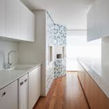 Kitchen, Medium Hardwood Floor, Wood Cabinet, White Cabinet, and Drop In Sink A  Photo 8 of 17 in Color Unites With Texture to Make This Brazilian Abode Appear Much Larger and Brighter