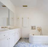 The bathroom in the master suite features a custom-made vanity and medicine cabinet. Tadelakt was used on the walls with Bulgarian limestone in the shower. The custom tiles were made by Haand Ceramics. The bathtub is a reclaimed piece with brass plumbing from Waterworks.