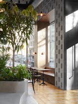 Dining, Pendant, Table, Chair, Cement Tile, Concrete, Wall, and Bench Large expanses of glass provide ample natural light, adding to the tropical vibe. 

  Dining Bench Chair Cement Tile Table Photos from This New Brooklyn Cafe Is Brewing Up More Than Tasty Artisanal Coffee