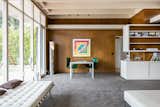 Living Room, Chair, Ottomans, Table, Carpet Floor, Storage, Track Lighting, Bench, and Floor Lighting Original wood paneling lines the walls.  Photo 8 of 13 in Case Study House #18 in L.A. Hits the Market at $10M and Includes Plans From Tom Kundig