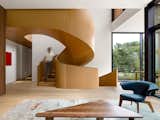 A wood-clad spiral staircase connects the living room to the second-floor master suite.&nbsp;