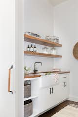 Laundry Room, Wood Counter, and White Cabinet The laundry room is simple and efficient.  Search “deluxe-laundry-basket-.html” from A Sleek Lake Tahoe Retreat Shows Off an Impressive Art Collection