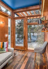 Living Room, Medium Hardwood Floor, Wall Lighting, Chair, Sofa, and Shelves One challenge Latimer faced was that Funke wanted natural light, but also a sense of privacy.  Photo 3 of 12 in This Tiny Home and Writing Studio Was Invented for a Children’s Author