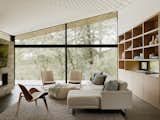 Large picture windows in the open living room frame the surrounding forest.