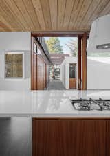 Kitchen, Wood Cabinet, Slate Floor, Cooktops, and Pendant Lighting A view from the kitchen to the exterior courtyard.

  Photos from A Historic Icelandic Midcentury Gets an Alluring Modern Twist