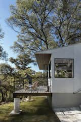 In the rear, a wooden deck is supported by concrete and shaded by a roof overhang. 

