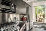 Kitchen, Microwave, Metal Backsplashe, Refrigerator, Dishwasher, Range, and Undermount Sink The open kitchen is small, yet highly efficient.  Photo 4 of 12 in Own This Iconic Glass Home in Salt Lake City For $950K