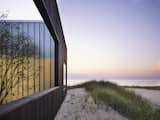 Exterior, House Building Type, Beach House Building Type, Wood Siding Material, and Flat RoofLine Here is a look at the colors of the beach at dusk against the charred timber exterior. 

  Photo 11 of 12 in Four Courtyards Form This Modern Waterfront Home