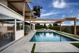 Outdoor, Large Pools, Tubs, Shower, Shrubs, Grass, Trees, Back Yard, Large Patio, Porch, Deck, and Hanging Lighting Clean lines and midcentury vibes surround the outdoor pool. 

  Photos from A Widely Published Midcentury in L.A. Hits the Market at $6.9M
