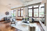 Living Room, Chair, Coffee Tables, Pendant Lighting, Sofa, Table Lighting, Medium Hardwood Floor, Rug Floor, and Wall Lighting The unit has an industrial loft-like feel.  Photo 3 of 9 in Grab This Dazzling Detroit Loft in a Historic School Building For $450K