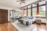 Bedroom, Medium Hardwood Floor, Night Stands, Bed, Table Lighting, and Rug Floor Large windows allow ample light to flood into the bedrooms. 

  Photo 7 of 9 in Grab This Dazzling Detroit Loft in a Historic School Building For $450K