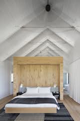 The master bedroom features vaulted ceilings and a light-wood wall to break up the space.&nbsp;