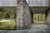 Exterior, Flat RoofLine, Stone Siding Material, House Building Type, Beach House Building Type, and Wood Siding Material The home cantilevers out over the series of stone-retaining walls.  Photo 3 of 11 in A Gorgeous Refuge Treads Lightly on its Surrounding Nature Reserve