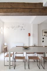 Dining Room, Light Hardwood Floor, Chair, Wall Lighting, and Table Exposed wooden beams add an element of warmth to the space. 

  Photos from A Parisian Townhouse Is Reborn as a Luminous Art Gallery