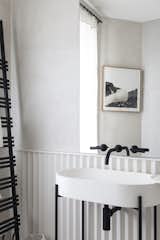 A sculptural pedestal sink accented by dark fixtures.&nbsp;