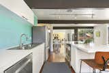 Kitchen, Refrigerator, Drop In, Dishwasher, Cooktops, Laminate, White, Track, and Dark Hardwood The kitchen from another angle looking into the living spaces.  Kitchen Dishwasher White Drop In Track Photos from A Handsome East Bay Eichler Lists For $875K