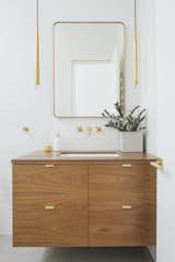 Bath, Subway Tile, Undermount, Wood, and Pendant Now, the bathroom is a beautiful blend of white, wood, and brass. The Lucent mirror and Aquitaine pendant lighting in burnished brass are from RH Modern. 

  Bath Undermount Wood Subway Tile Photos from A Dark Midcentury Becomes a Luminous Gem