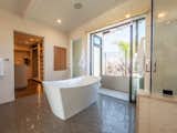 The large ensuite master bath opens to a balcony which has an outdoor shower and a green wall for privacy. High-end touches include wall-to-wall tiling, a steam shower, a freestanding soaking tub, and a Toto Neorest bidet toilet.