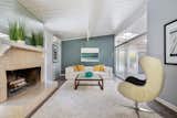Living Room, Track Lighting, Sofa, Wood Burning Fireplace, Chair, Medium Hardwood Floor, Standard Layout Fireplace, and Rug Floor The spacious living room also receives ample natural light via the atrium.

  Photos from An Updated Eichler in the Bay Area Lists For $1.25M