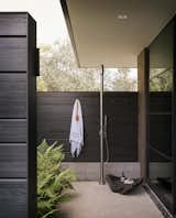 A serene outdoor shower space is surrounded by shou sugi ban wood.&nbsp;
