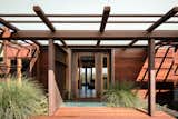 The façade juxtaposes the rich oxidized patina of Cor-ten steel with the deep, earthy tones of reclaimed redwood beams. 


