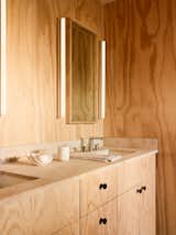 The master bath is clad in plywood and features a custom vanity by Woodline Design paired with a Bourgogne limestone countertop with a honed finish by Fox Marble. The vanity mirror is a custom piece by Greg Nelson at GGD.