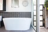 Bath Room, Freestanding Tub, Soaking Tub, Porcelain Tile Wall, and Porcelain Tile Floor Sliding doors can be opened for a true indoor-outdoor feel.  Photo 14 of 19 in An Updated Eichler With an Indoor-Outdoor Master Bath Seeks $1.15M