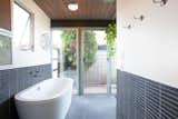 Bath Room, Freestanding Tub, Soaking Tub, Porcelain Tile Wall, Ceiling Lighting, and Porcelain Tile Floor Beautifully tiled, the freestanding soaking tub is an excellent addition to the space.  Photos from An Updated Eichler With an Indoor-Outdoor Master Bath Seeks $1.15M