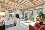 The bright and airy master bedroom features expansive glazing and has a high ceiling with exposed beams.

