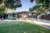 Exterior, Gable, Brick, House, Wood, Glass, and Mid-Century The spacious backyard features mature trees, including avocado, that shade the home in the afternoon.  Exterior House Glass Gable Mid-Century Photos from This Light-Filled Orange County Eichler Home Just Listed For $1.1M
