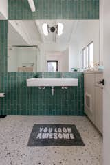 After: MYD Studio specified a floor-to-ceiling wall of aquamarine tile by Heath Ceramics to create a striking backdrop for the mounted sink. The terrazzo floors are from Concrete Collaborative.&nbsp;