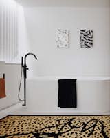 A bold black and white bathroom with a graphic leopard print rug.&nbsp;
