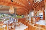 The curvilinear individually-treated Douglas Fir beams cascade out from the central atrium. This is a look at the kitchen which features built-in teak cabinetry and an original light fixture over the table.